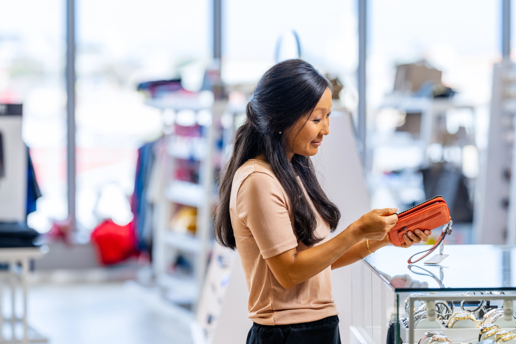 Kvinna i butik som tittar på en orange väska