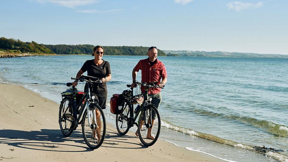 Par med sykkel på stranden.jpg