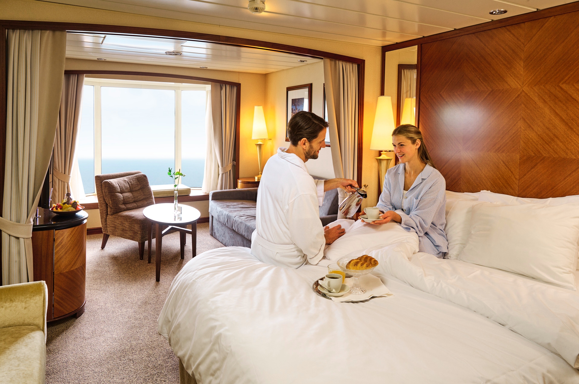 Par som drikker kafe i sengen i en suite